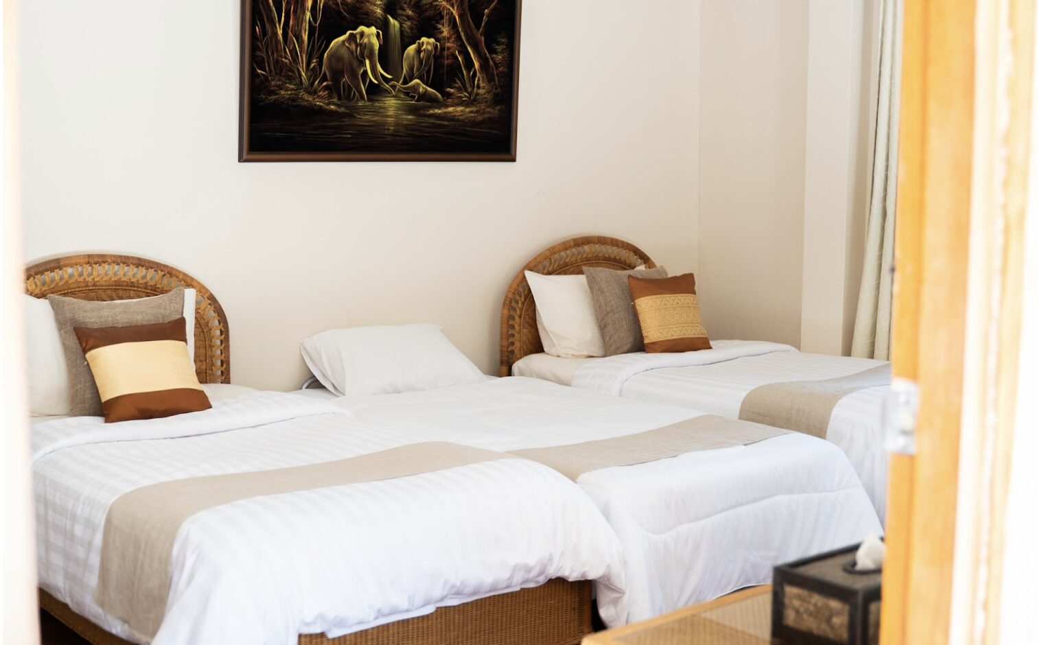 A bright shared bungalow room with two beds and woven headboards